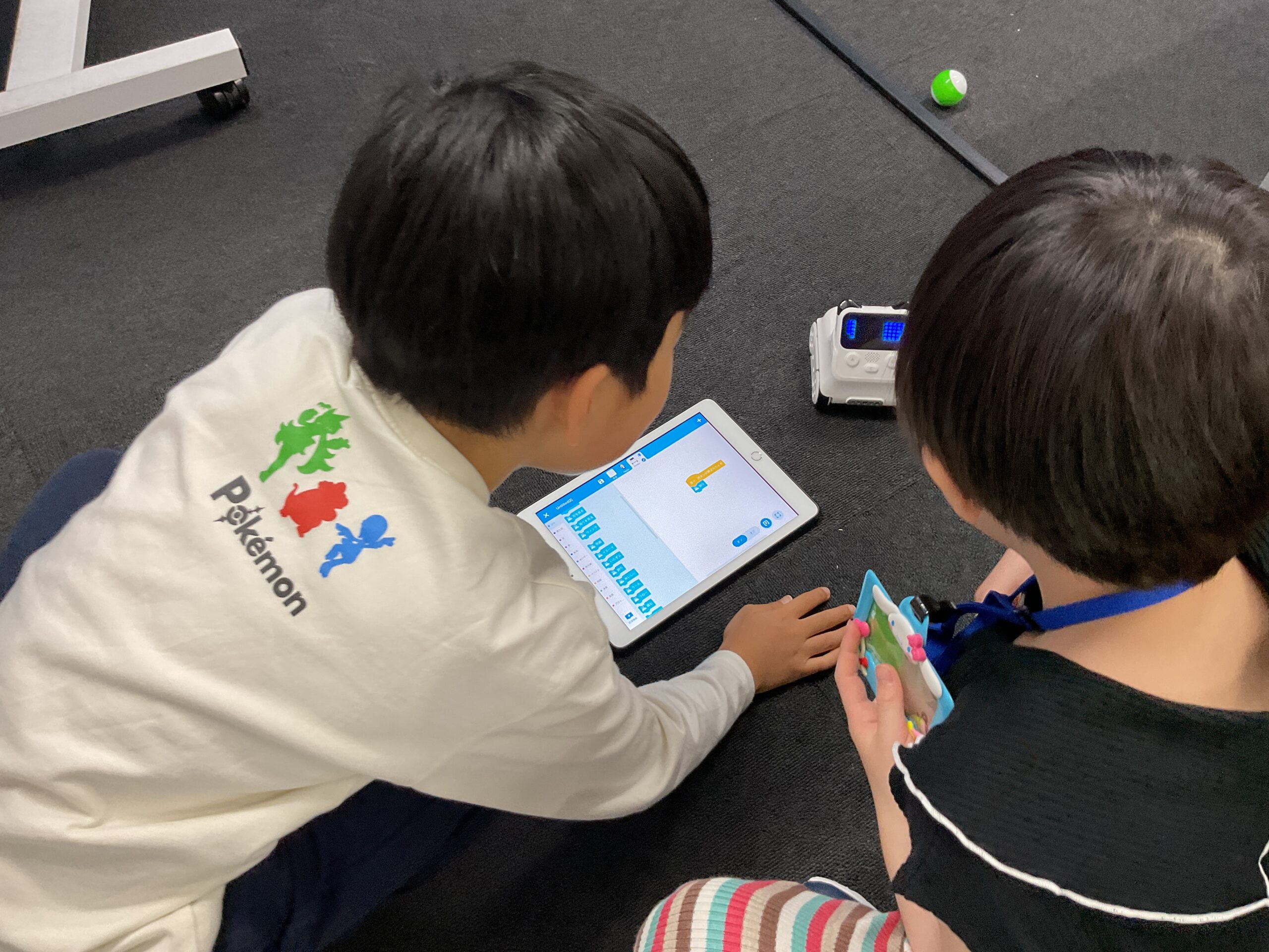 タブレットとロボットを使ってプログラミングする子どもたち